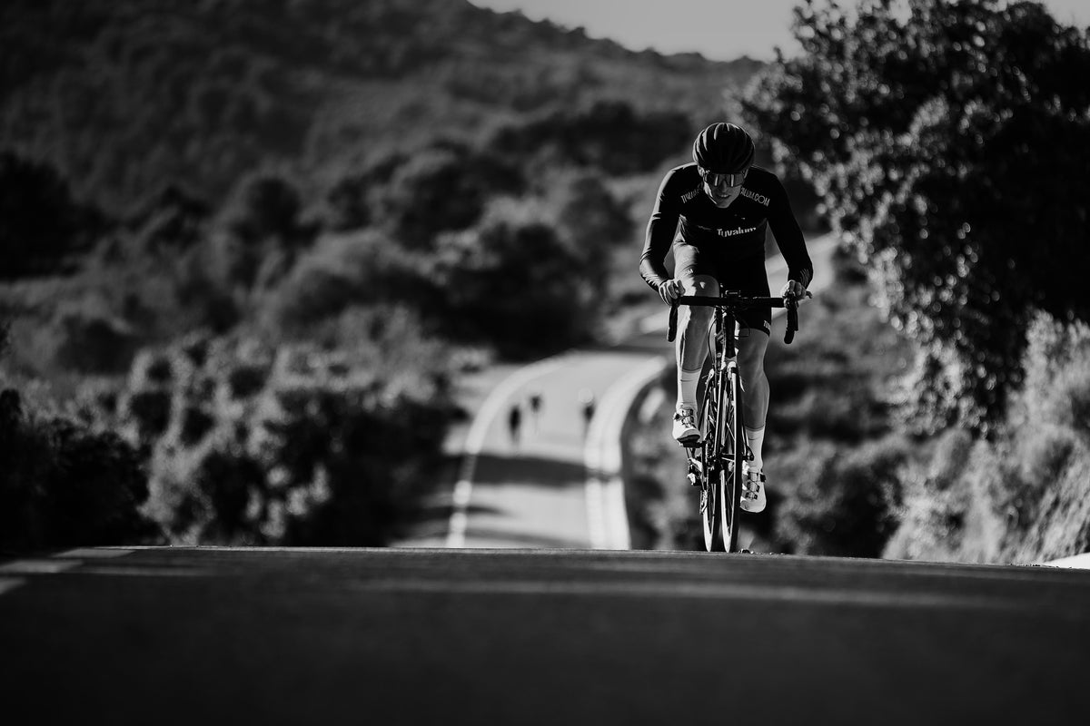 A road cyclist cresting a climb on an empty country road